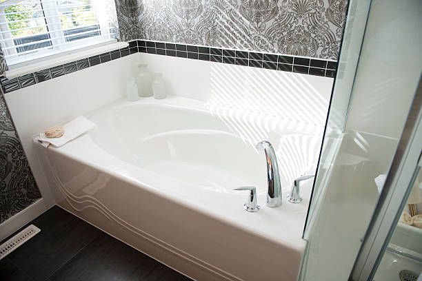 A nice new bathtub inside a modern bathroom with black and white tiles.