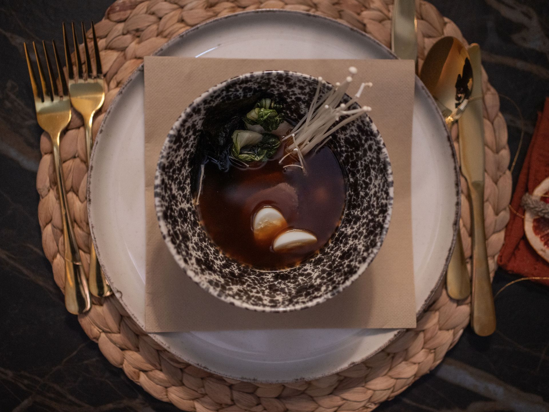 Een kom soep staat op een bord met bestek