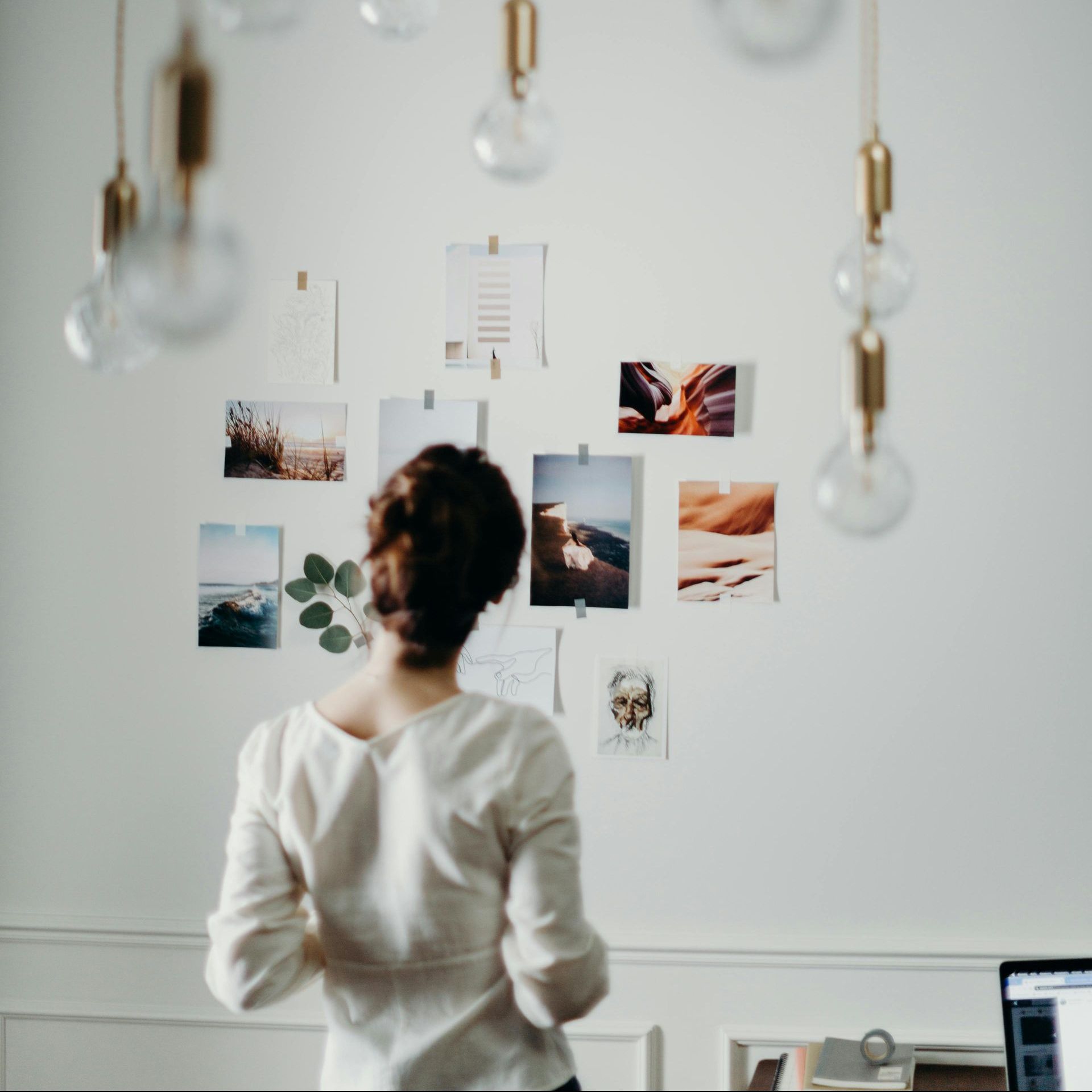 Eine Frau steht vor einer Wand, an der einige Fotos hängen. 