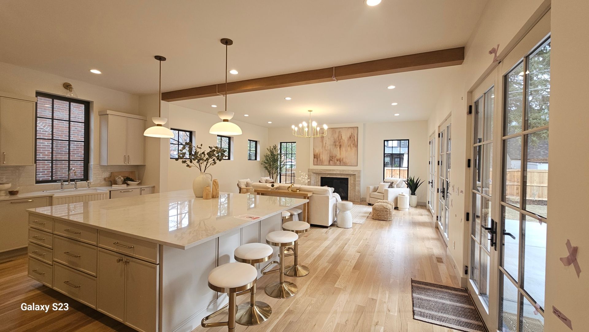 Modern kitchen and living room with island, wood floors, and outdoor access.
