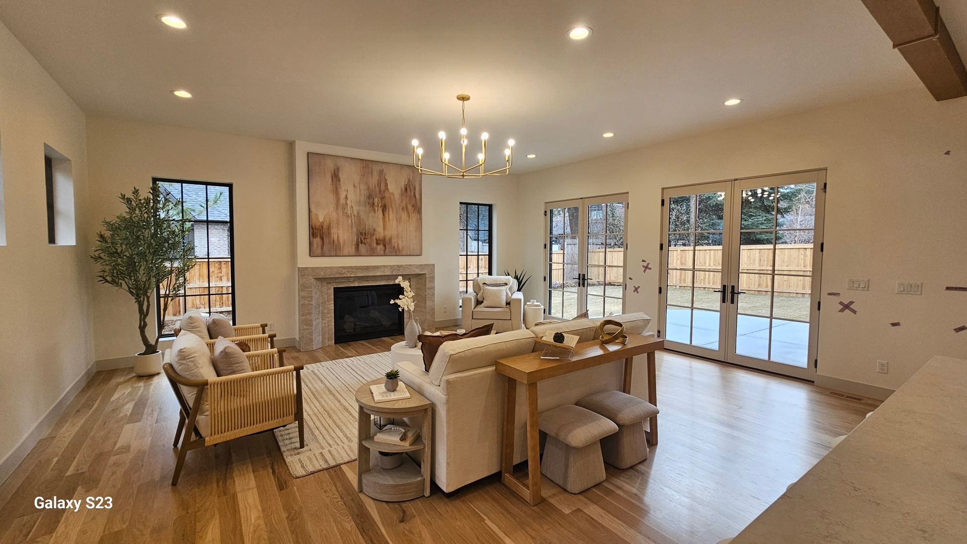 Spacious living room with hardwood floors, fireplace, and large windows leading to an outdoor patio.