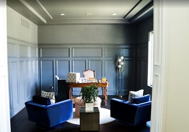 A living room with blue chairs and a desk