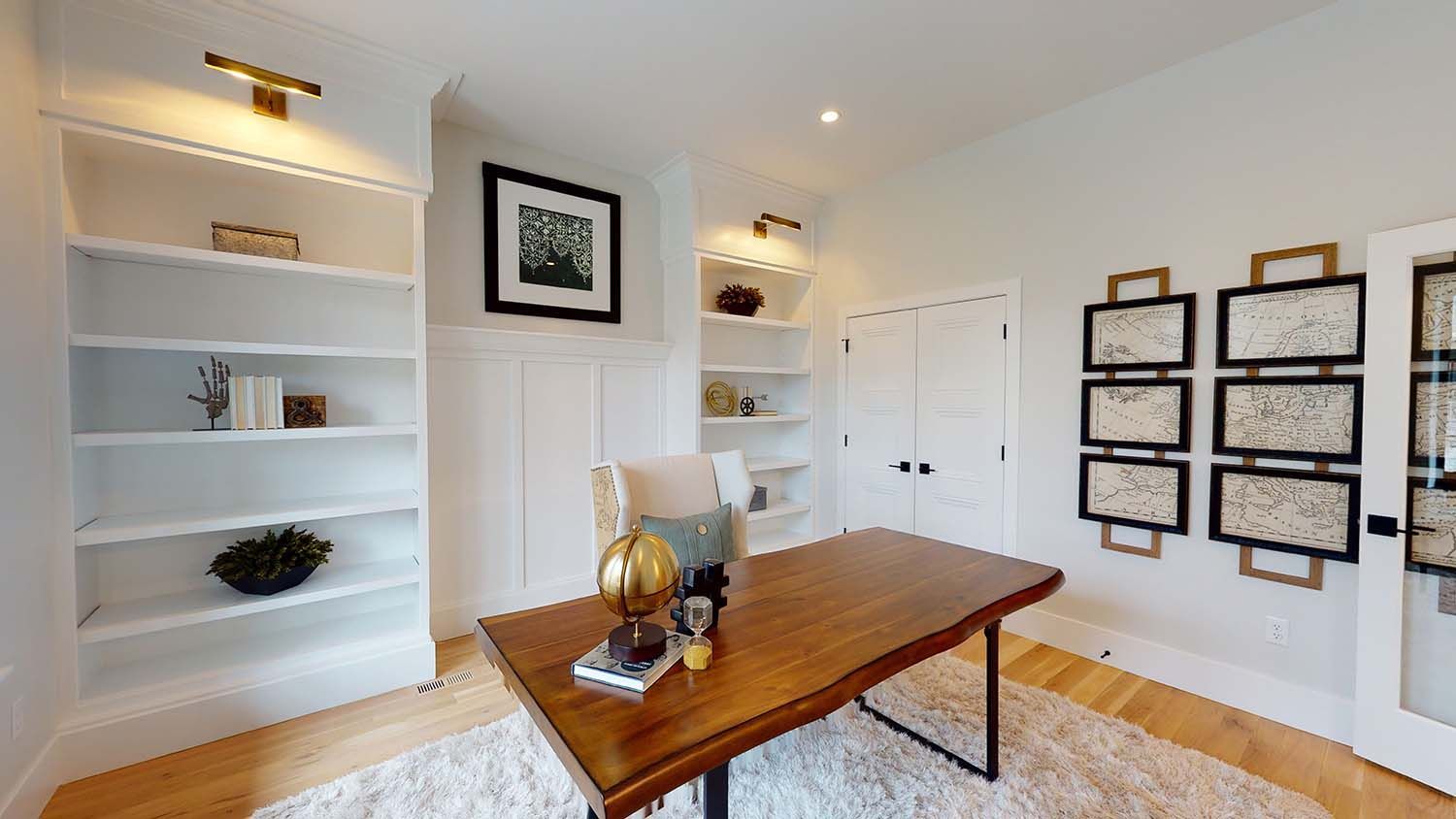 A home office with a wooden desk and white shelves.