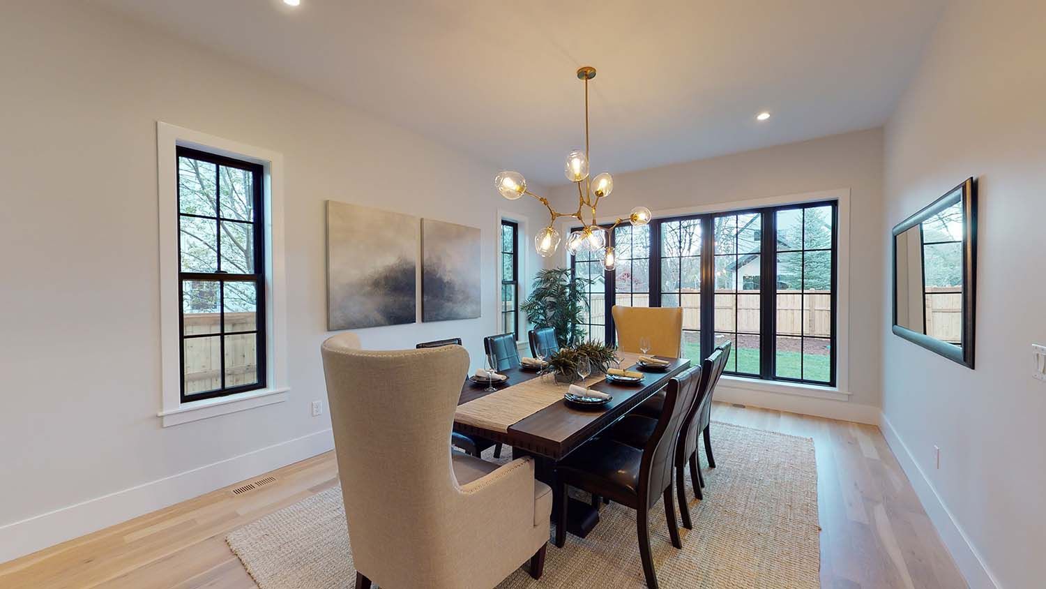 A dining room with a long table and chairs and a chandelier.