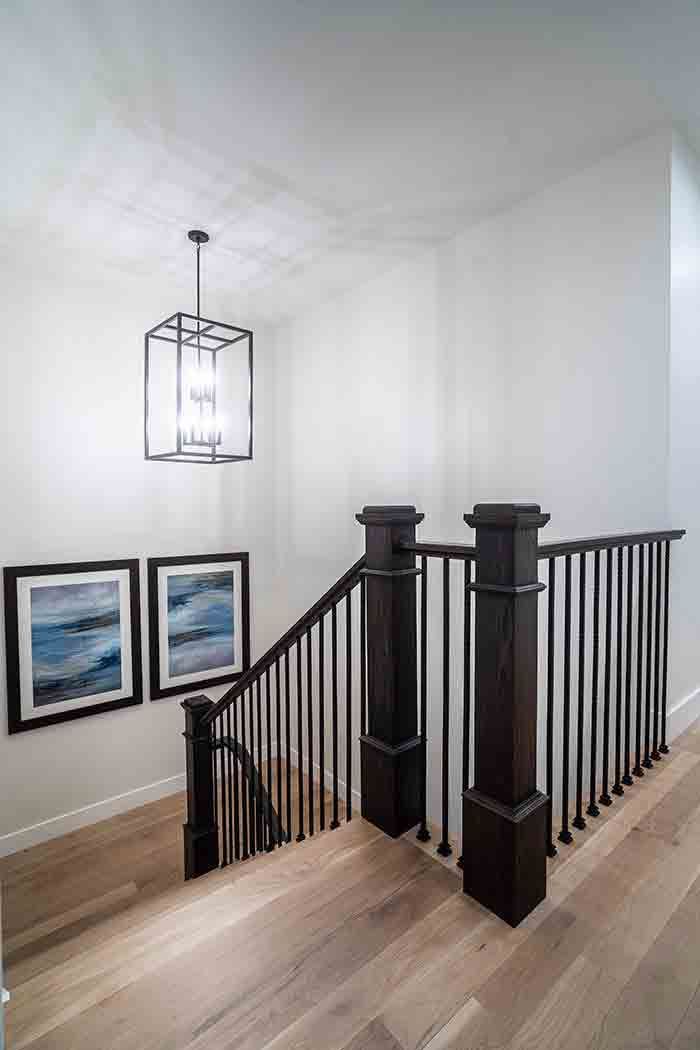 A staircase with a wooden railing and a chandelier hanging from the ceiling.