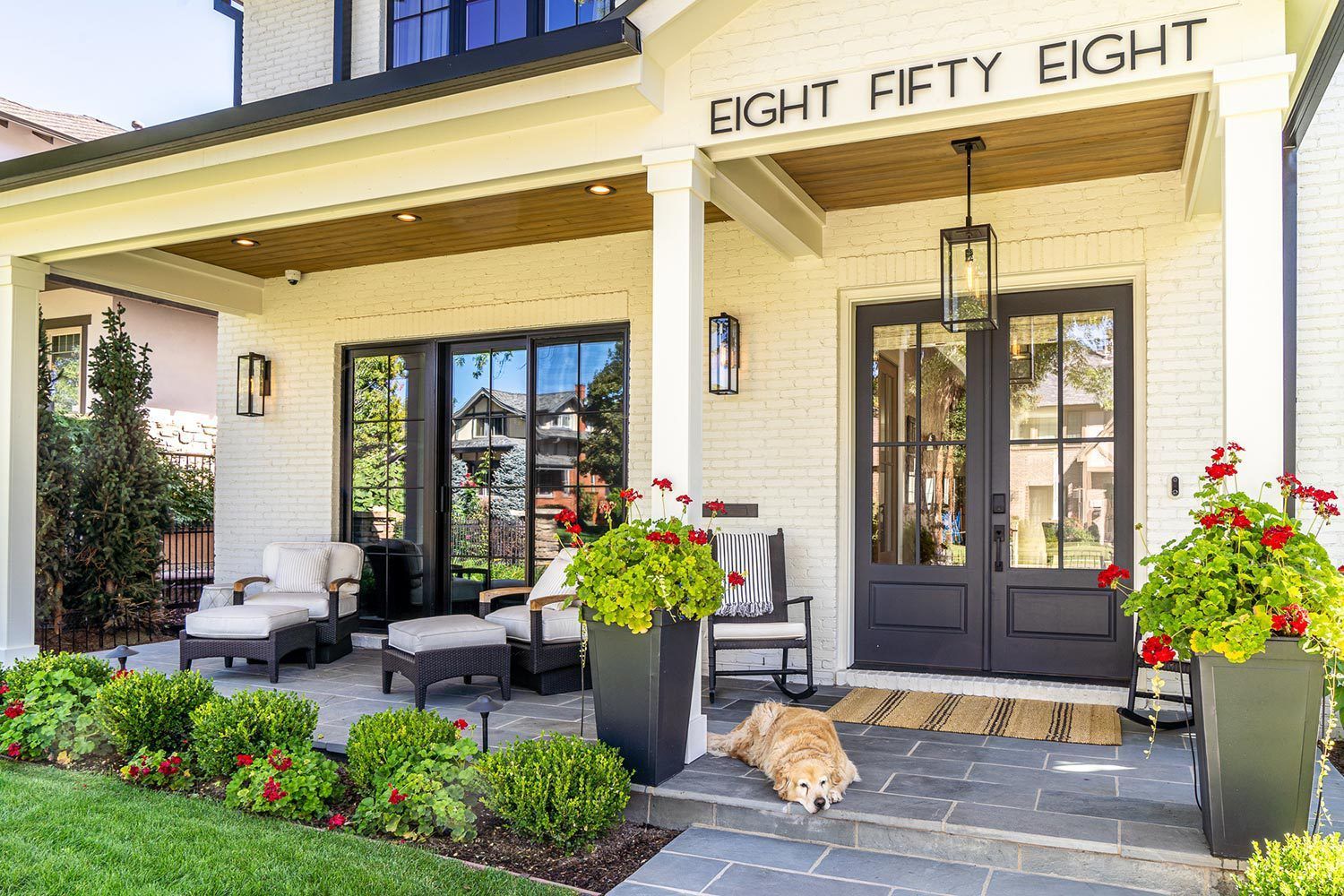 A dog is sitting on the porch of a house.