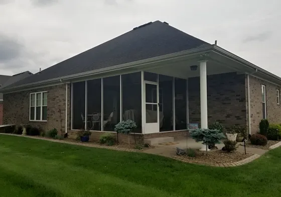 A brick house with a screened in porch and patio.
