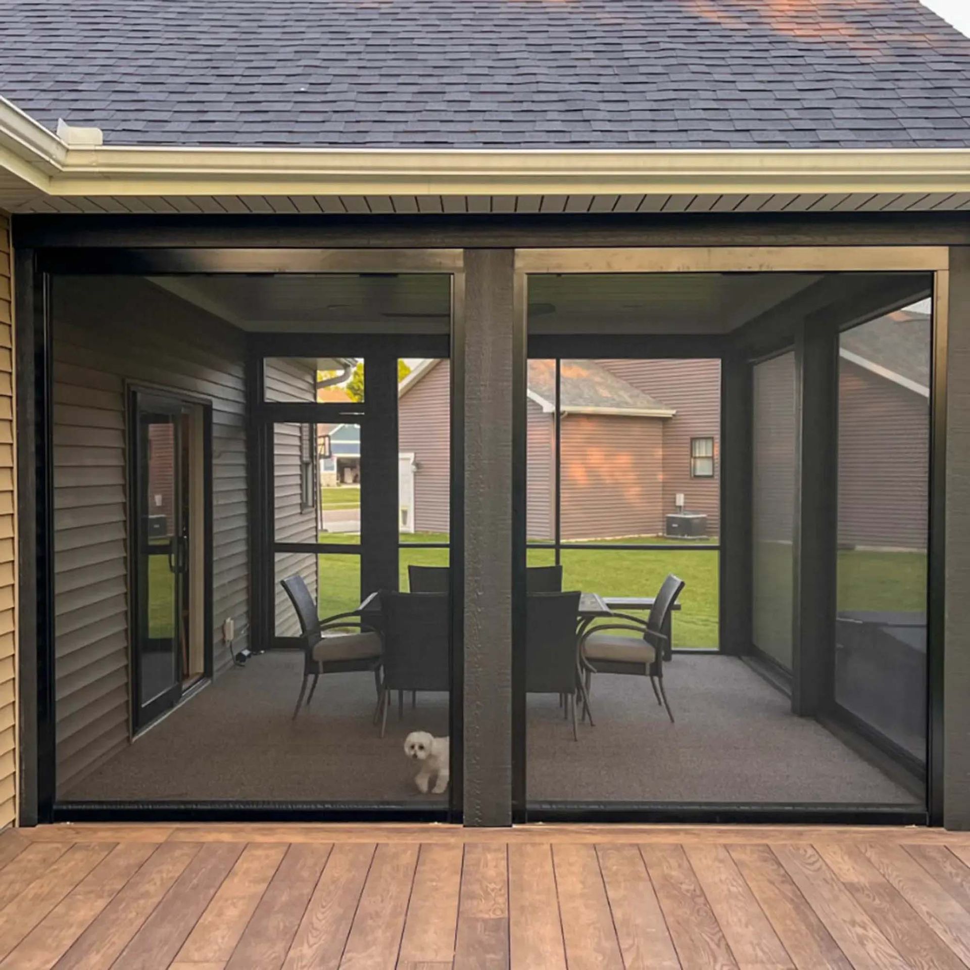 A screened in porch on the side of a house.