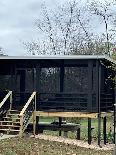 A screened in porch in front of a brick house