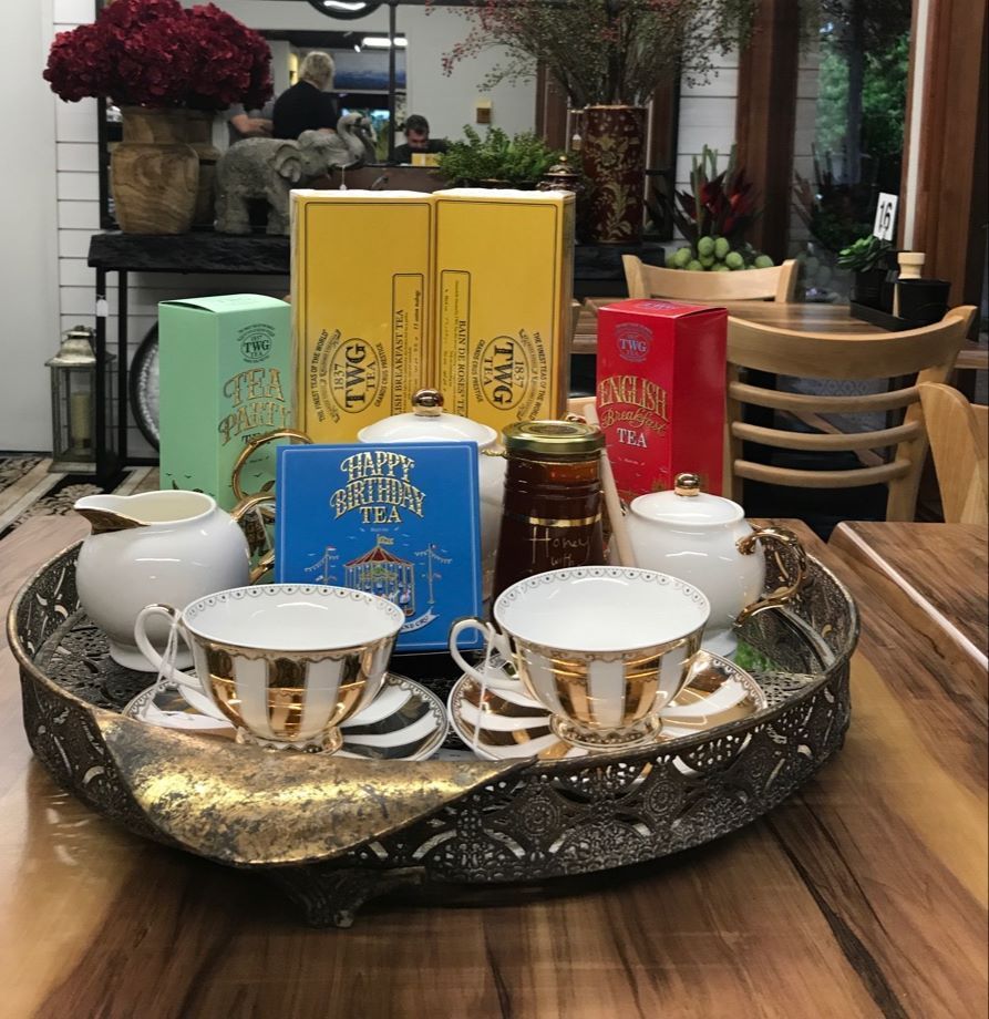 A tea set with cups, saucers, and tea boxes on a decorative tray.