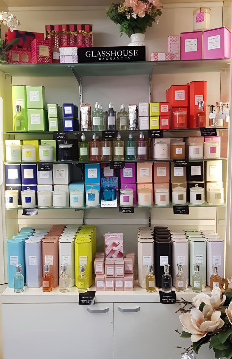 Shelves displaying colorful boxed candles and perfumes in a store, with the brand 
