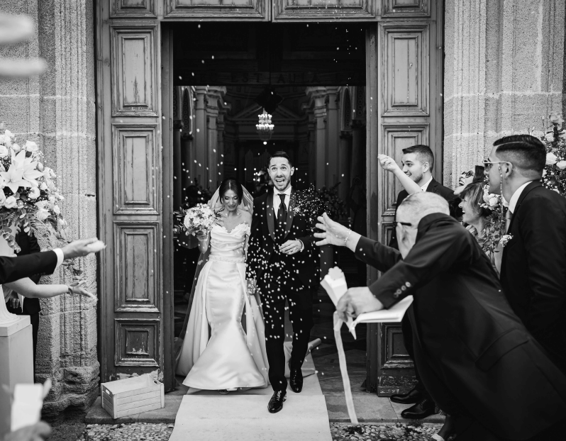 Una foto in bianco e nero di una sposa e uno sposo che escono da una chiesa.