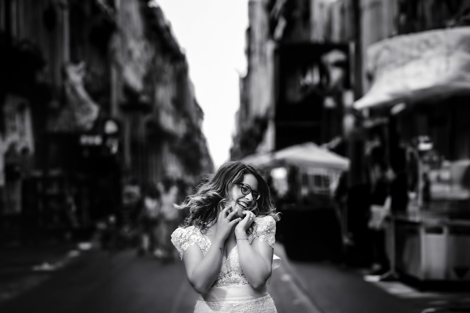 Una donna vestita di bianco è in piedi su una strada cittadina.