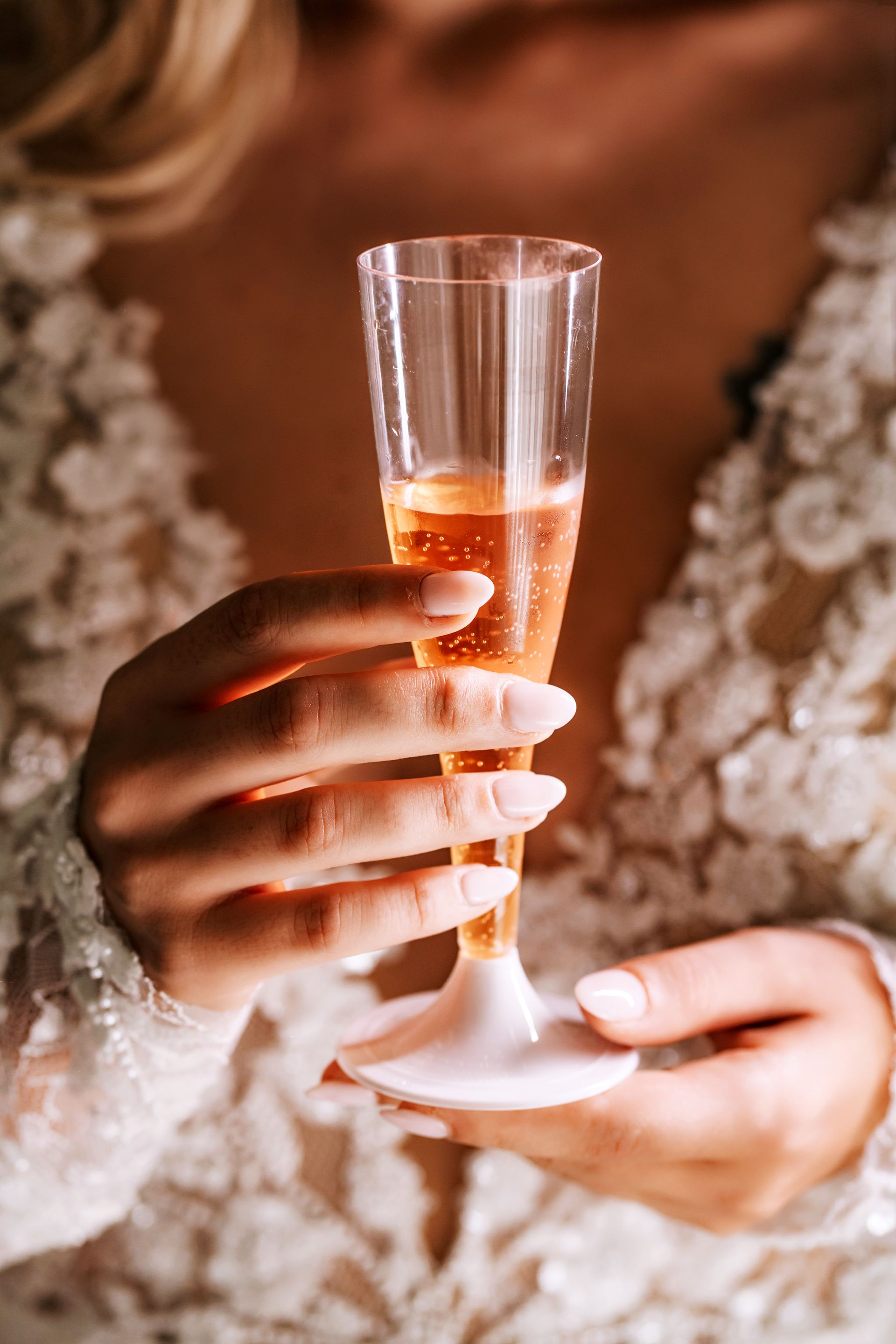 Una donna in abito da sposa tiene in mano un bicchiere di champagne.