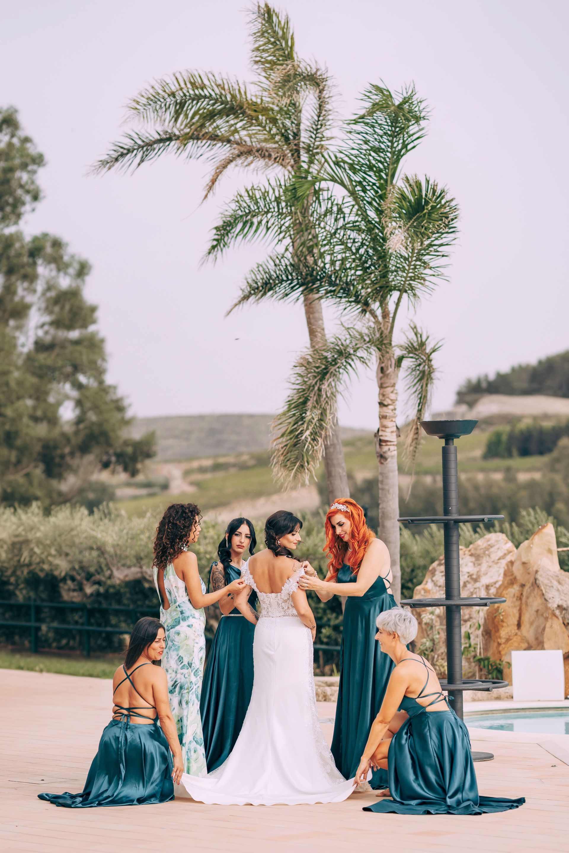 Una sposa e le sue damigelle posano per una foto davanti a una palma.