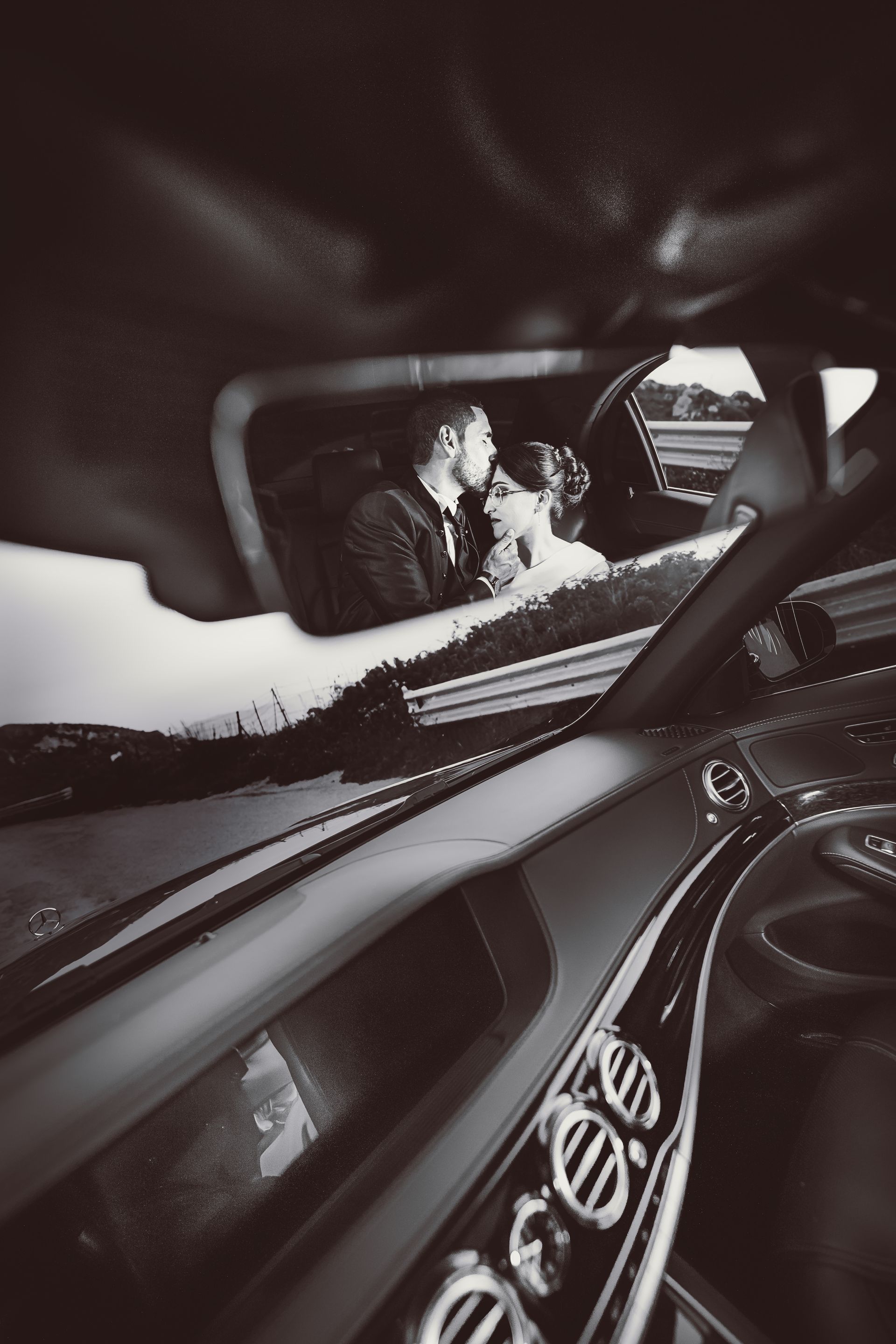 Una foto in bianco e nero di una sposa e uno sposo in macchina.