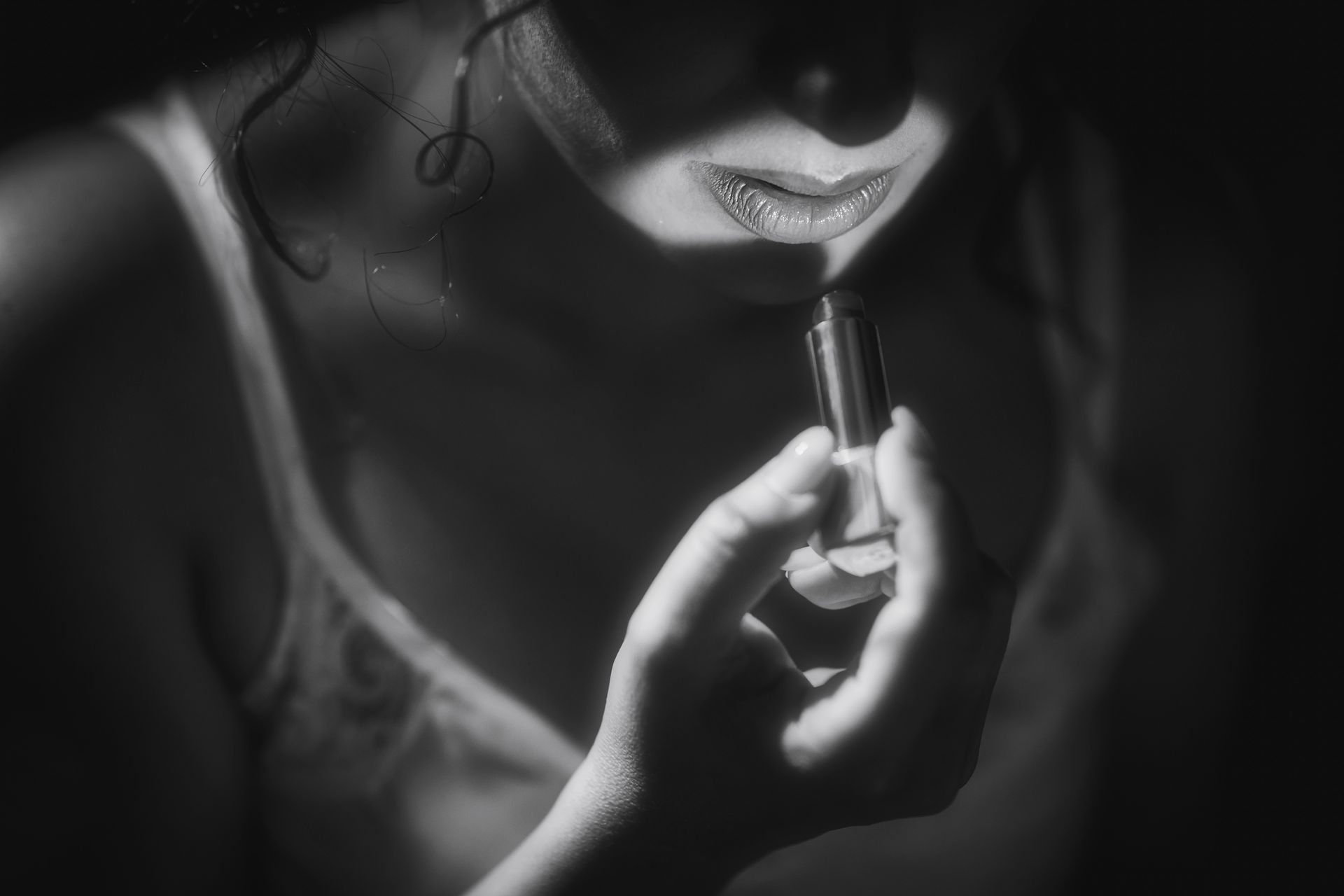 Una donna si mette il rossetto sulle labbra in una foto in bianco e nero.
