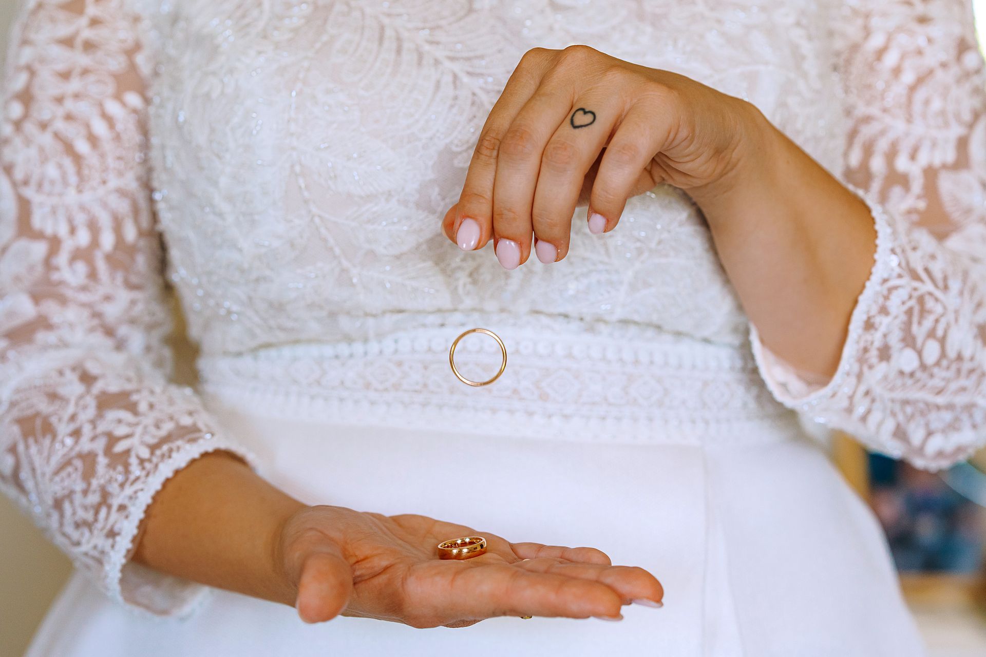 Una donna in abito da sposa tiene in mano due fedi nuziali.