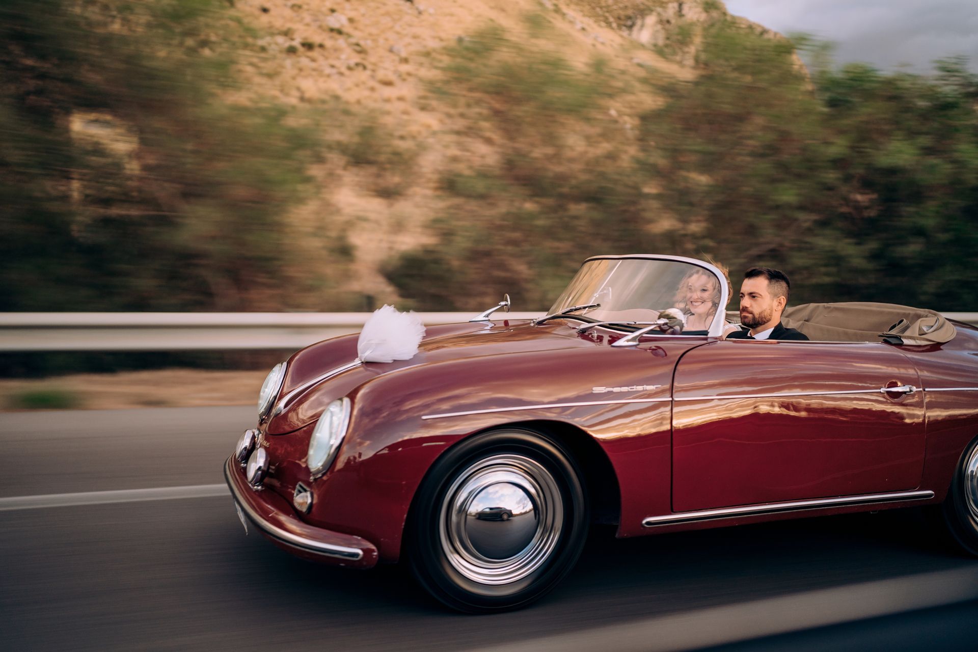 Un uomo e una donna guidano un'auto sportiva rossa su un'autostrada.