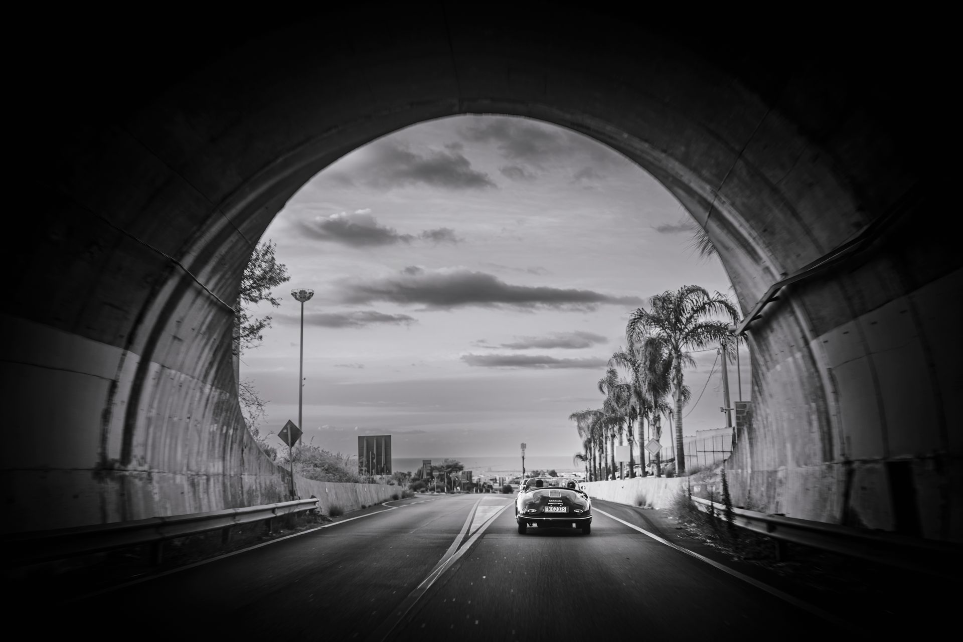 Una foto in bianco e nero di un'auto che attraversa un tunnel.