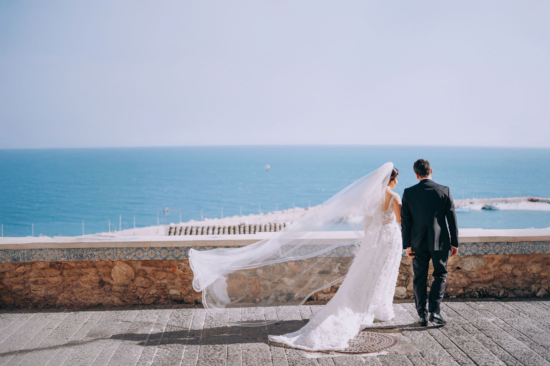 Una sposa e uno sposo stanno camminando verso l'oceano.
