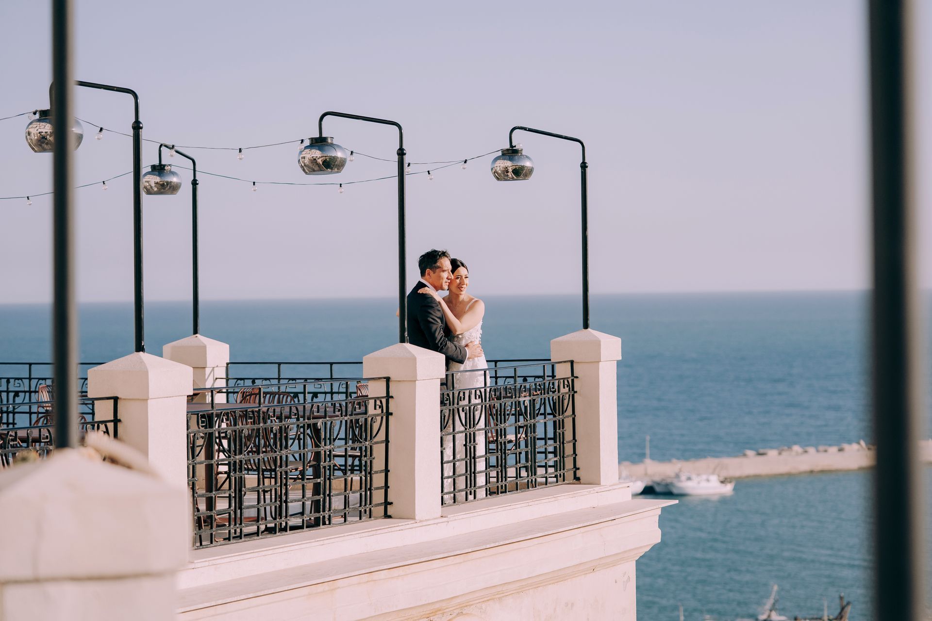 Una coppia di sposi sono in piedi su un balcone con vista sull'oceano.