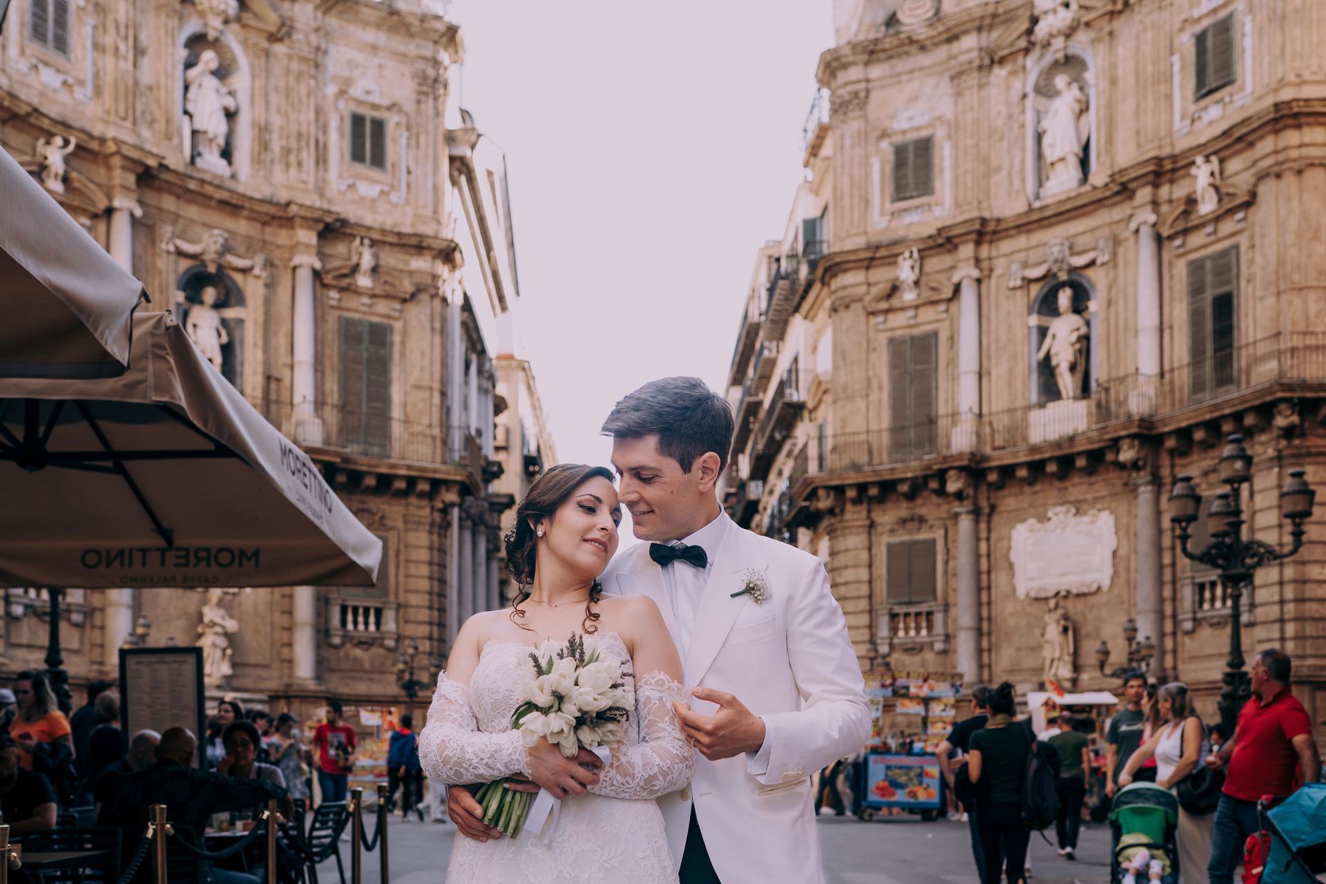 Una coppia di sposi posa per una foto in una strada cittadina.