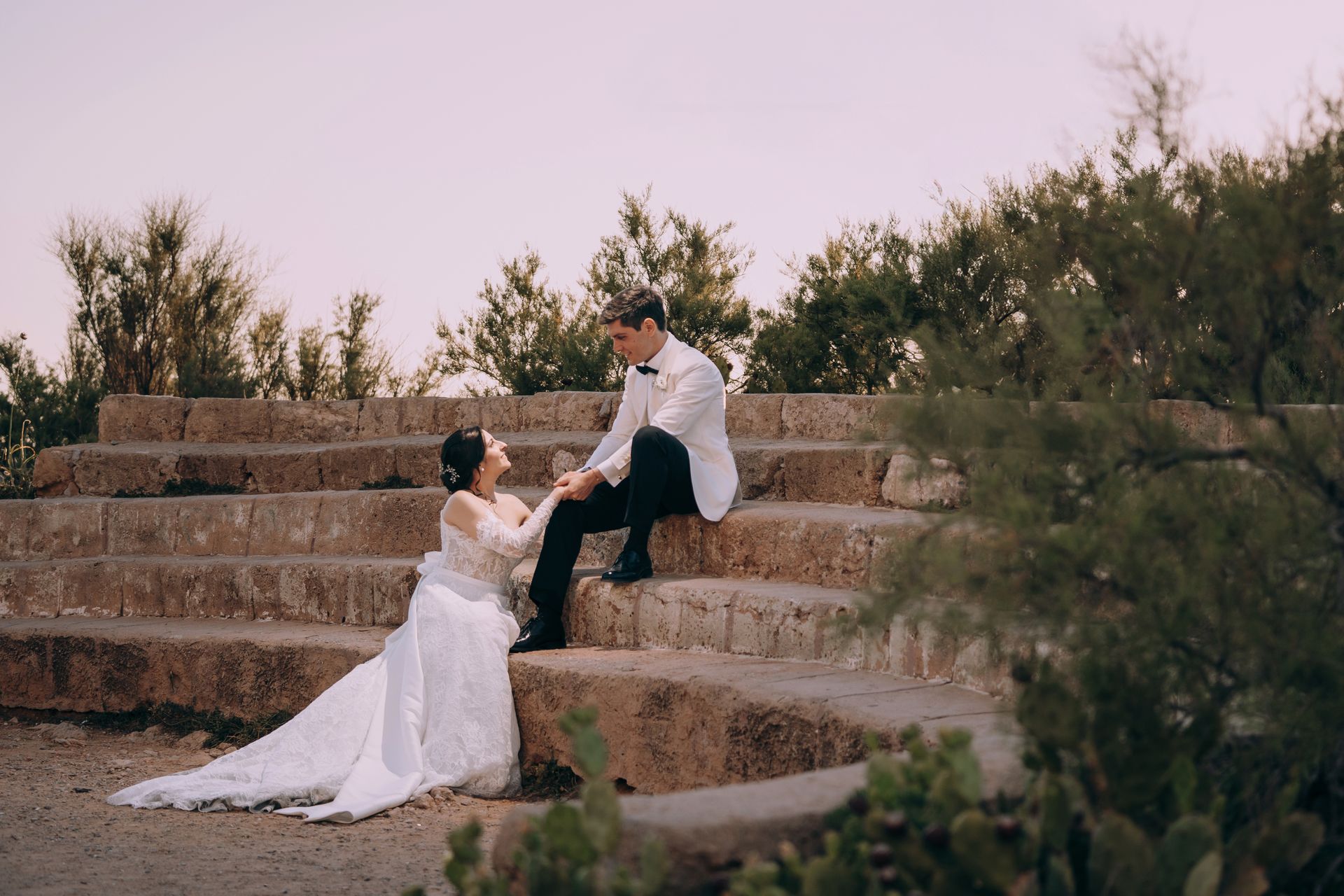 Una sposa e uno sposo sono seduti su una scalinata in pietra.