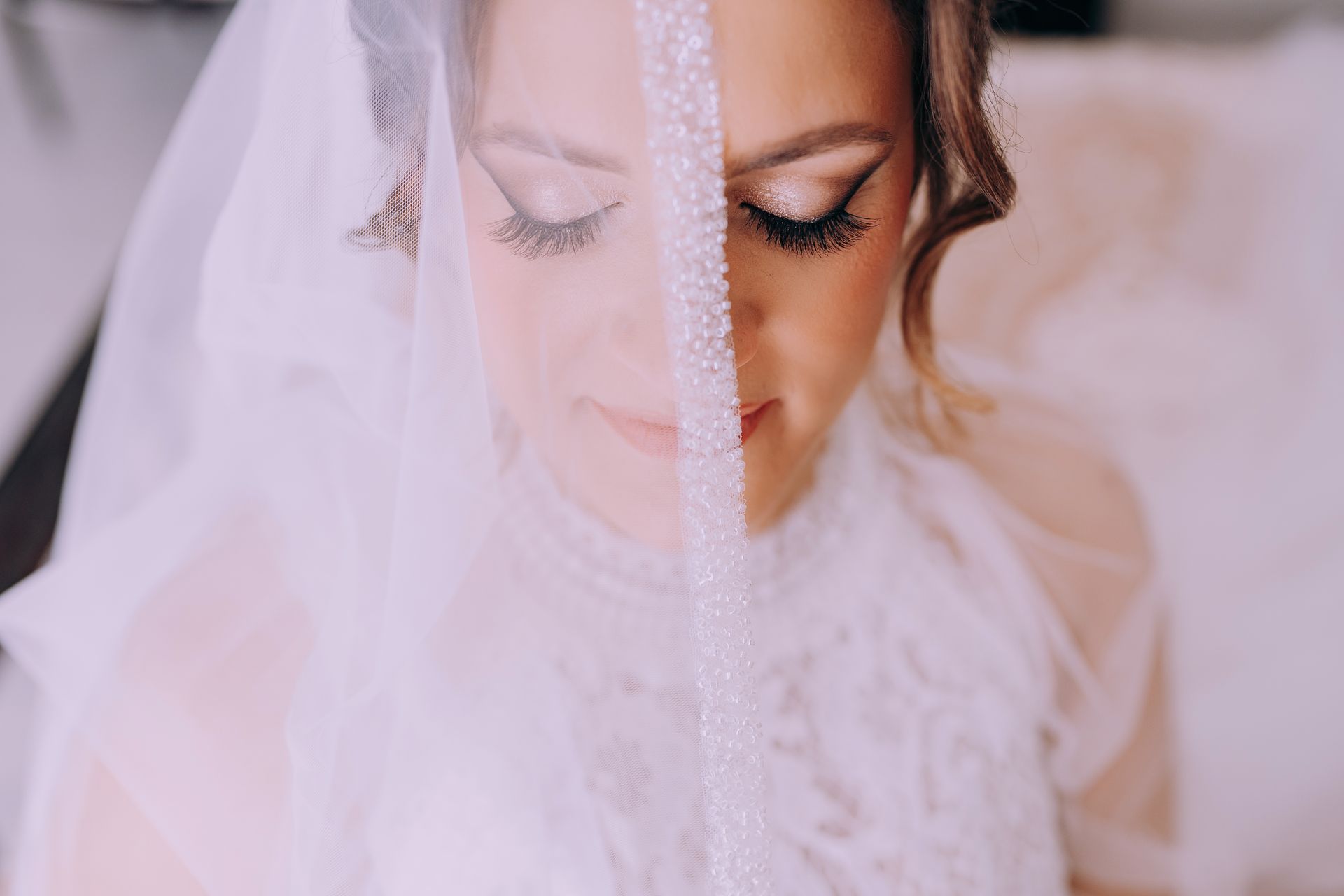 Primo piano di una sposa che indossa un velo e tiene gli occhi chiusi.