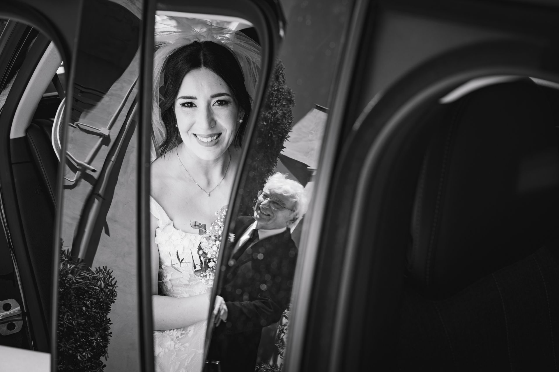 Una foto in bianco e nero di una sposa e uno sposo in macchina.