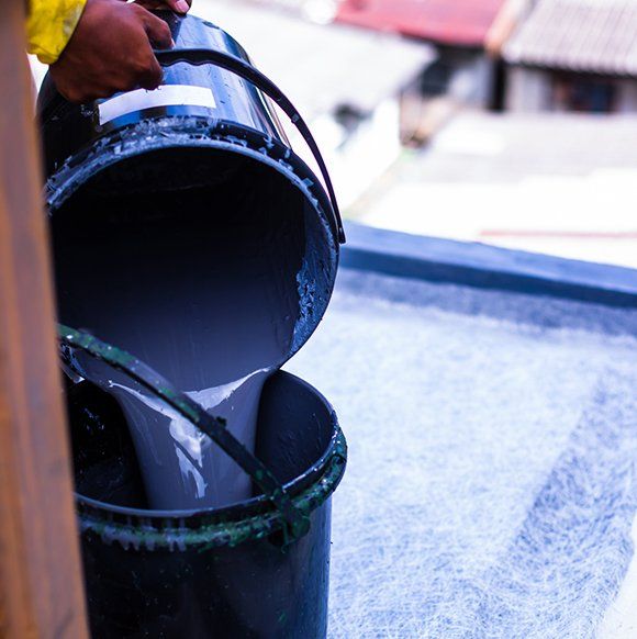 a person is pouring paint into a blue bucket