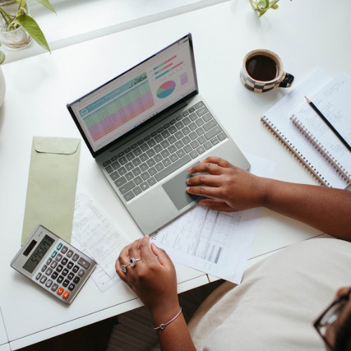 A person is sitting at a desk using a laptop and a calculator