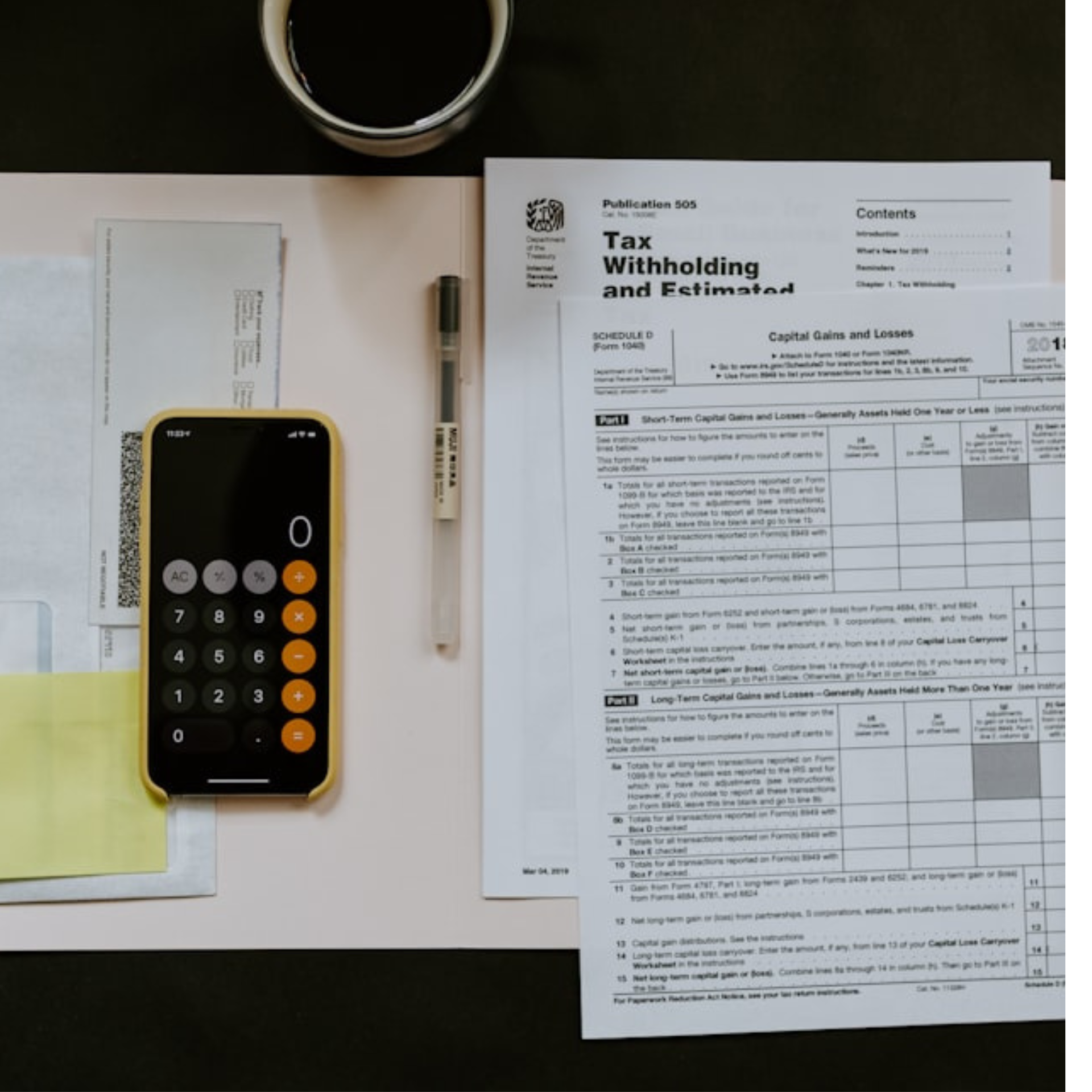 Tax forms, calculator, pen, coffee cup on a desk, suggesting tax preparation or financial planning.