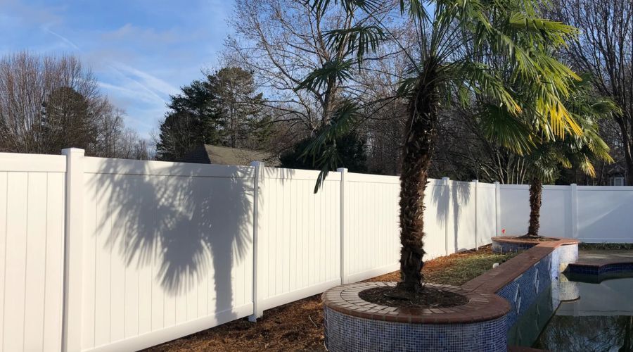 White vinyl privacy fence installed by a pool, compliant with Charlotte, NC fence permit regulations