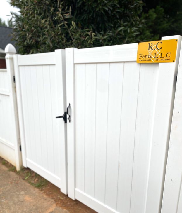 White vinyl gate in a residential setting with a business sign that reads