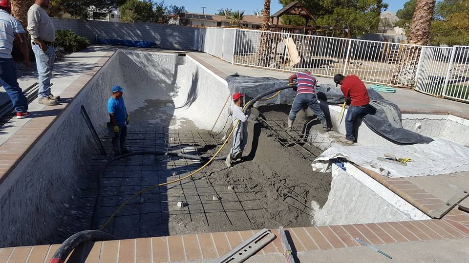 A group of construction workers are working on a swimming pool.
