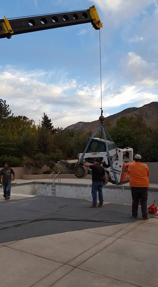 A crane is lifting a vehicle into a pool.