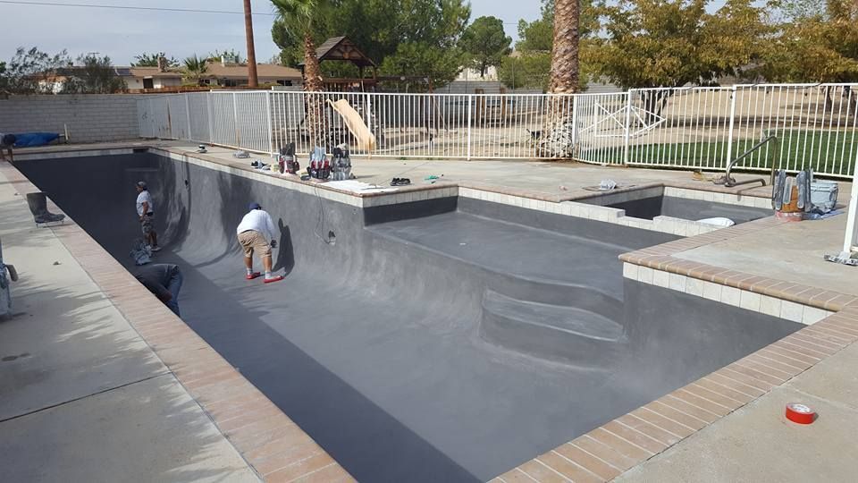 A man is working on the side of a swimming pool.