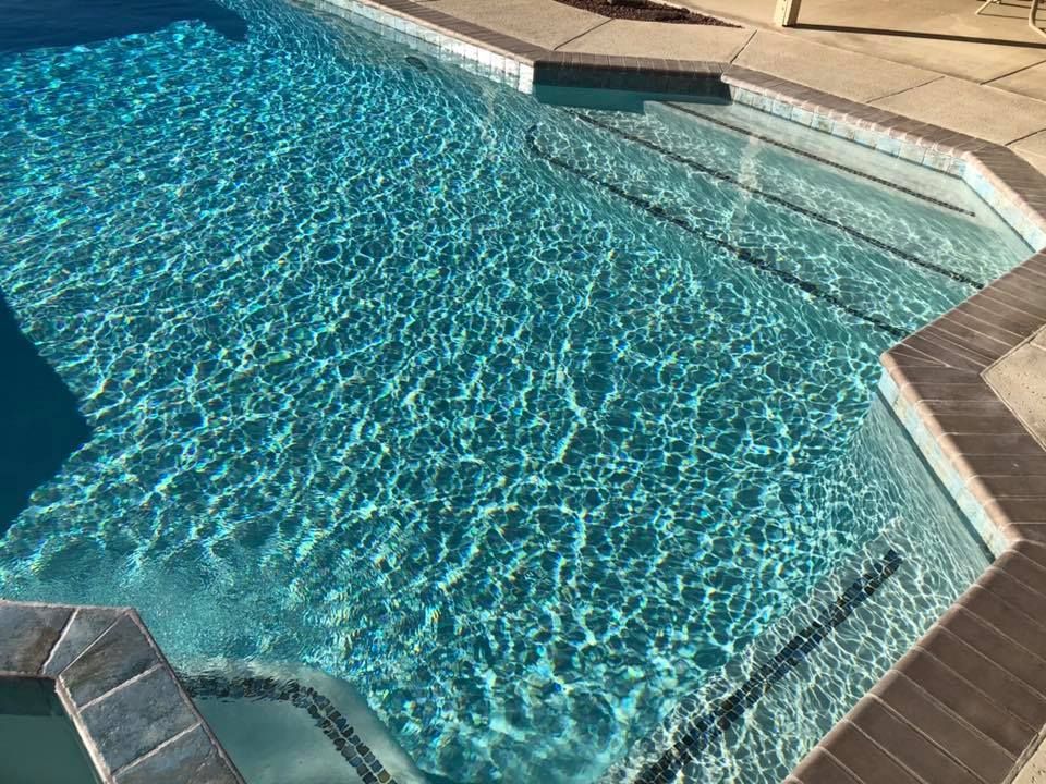 A large swimming pool filled with blue water and steps.