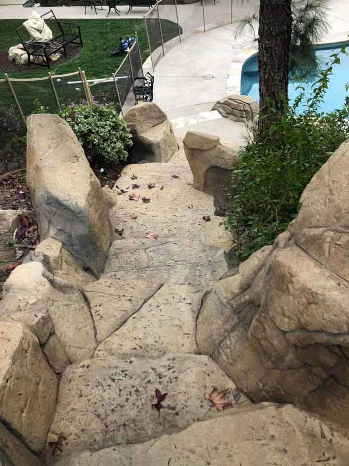 A set of stairs leading up to a pool surrounded by rocks.