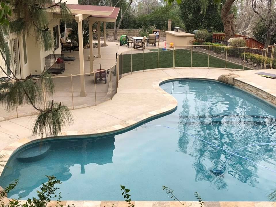 A large swimming pool is in the backyard of a house.