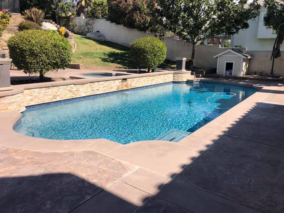 A large swimming pool with a dog house in the background