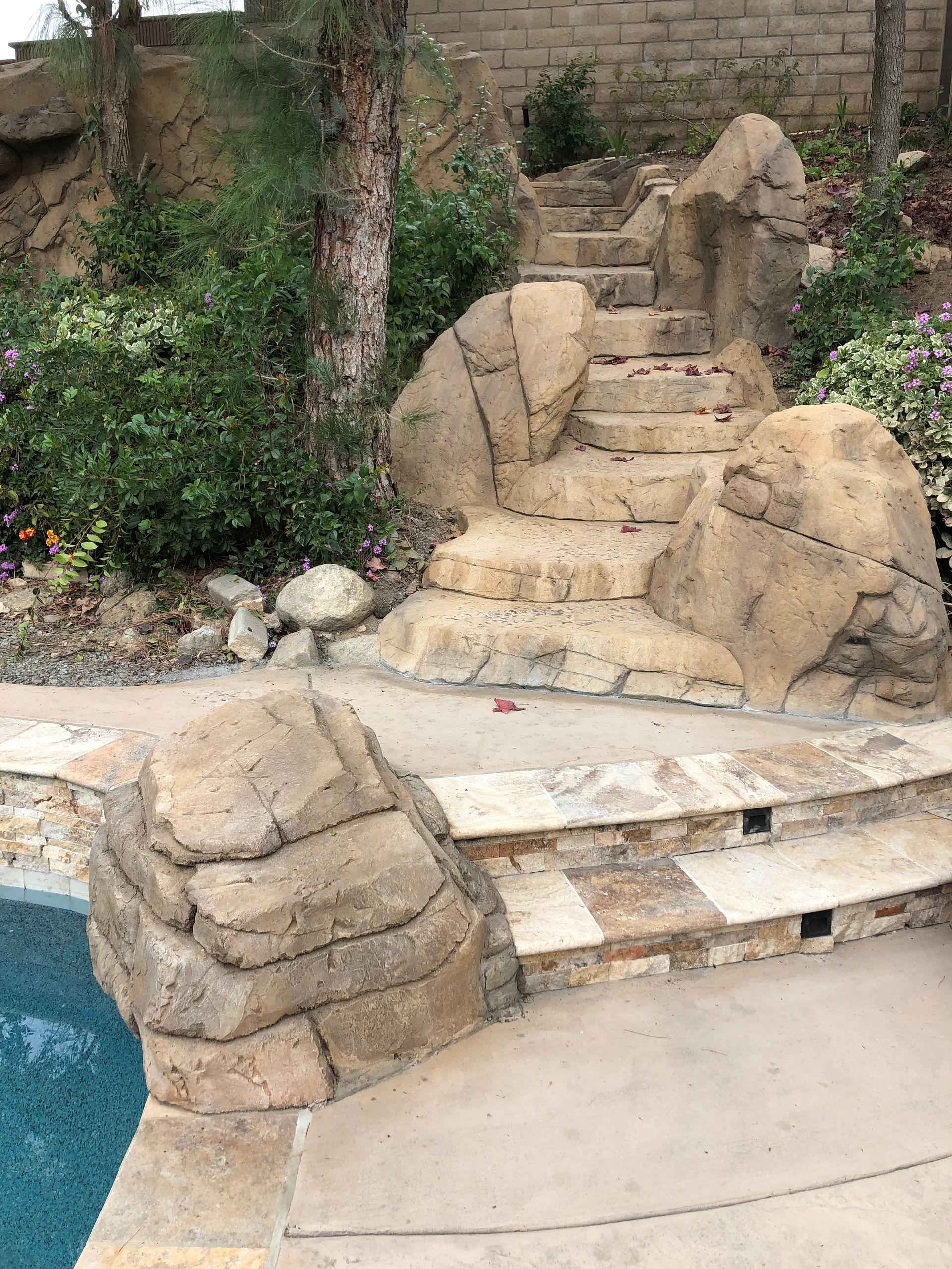 There are stairs leading up to a swimming pool surrounded by rocks.