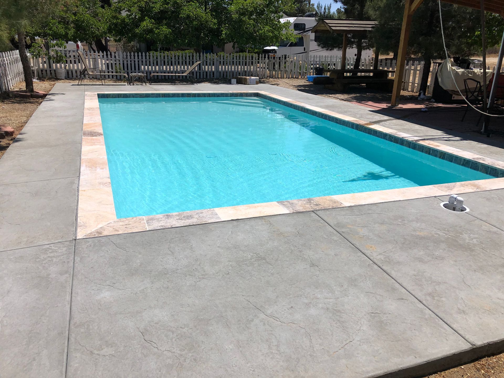 A large swimming pool is surrounded by a concrete patio