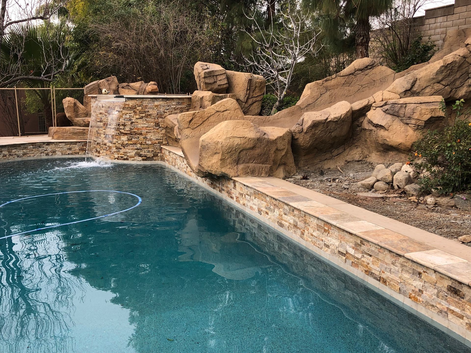 A large swimming pool with a waterfall and rocks in the background.