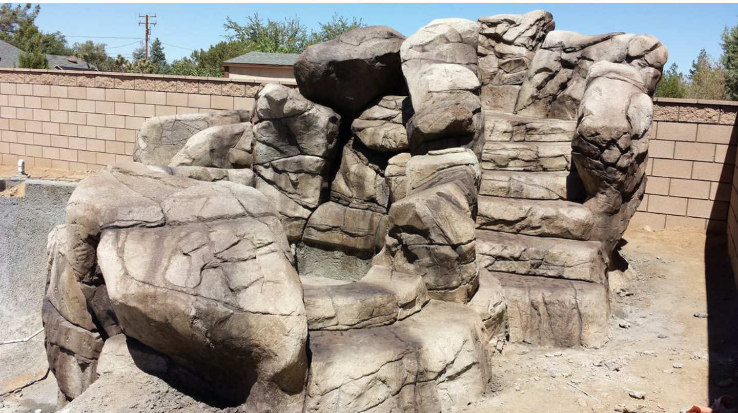 A large rock formation with a brick wall in the background