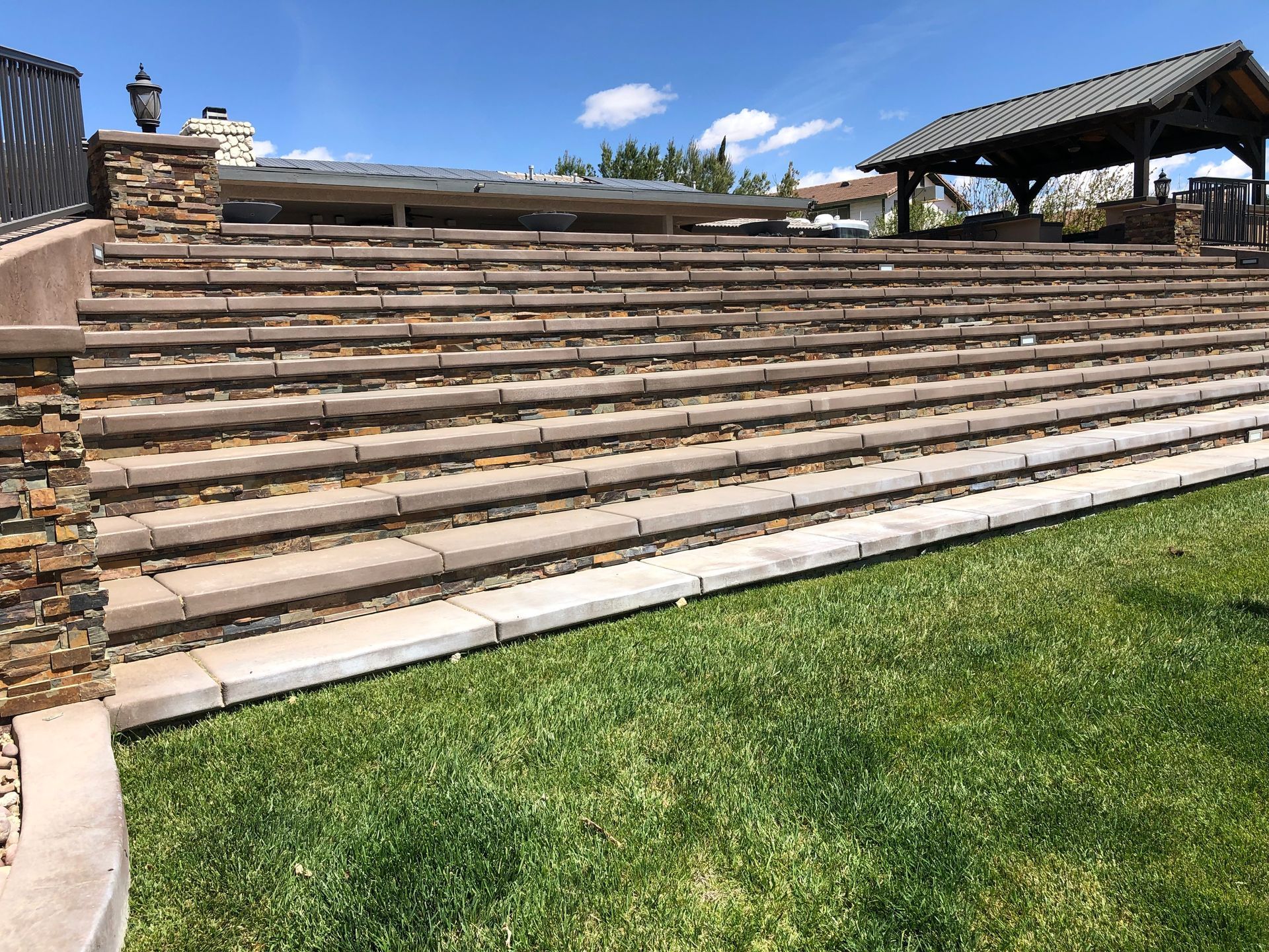 A stone wall with stairs leading up to a gazebo in the background.