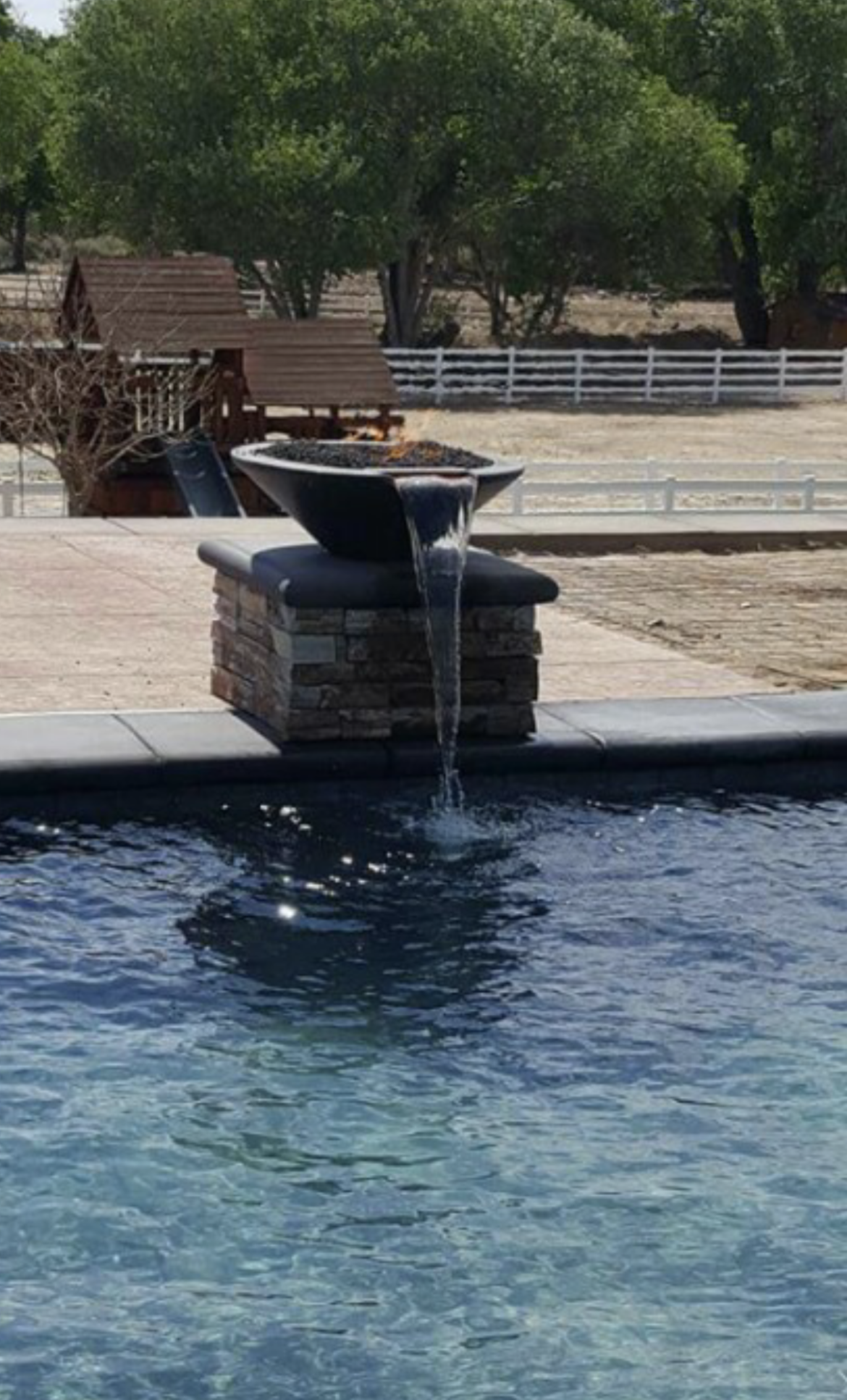 A fountain in the middle of a pool with trees in the background