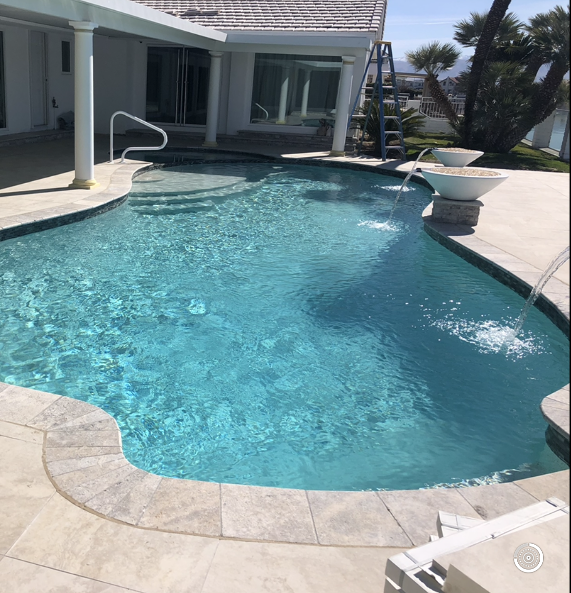 A large swimming pool is in the backyard of a house.