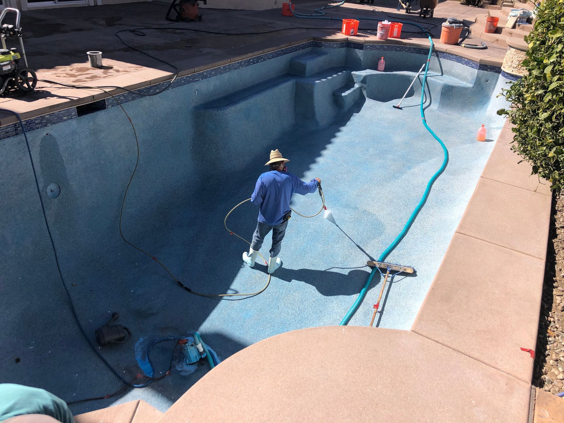 A man is cleaning a swimming pool with a hose